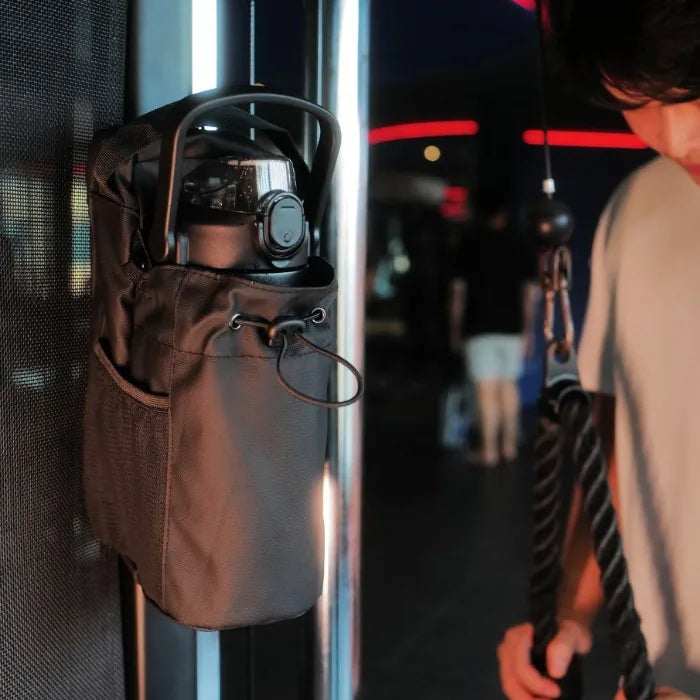 Bolsa magnética para gimnasio con portabotella colgada en máquina de entrenamiento durante rutina